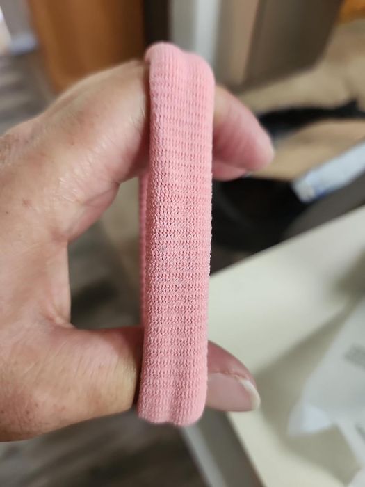 A hand holding a pink elastic hair band.