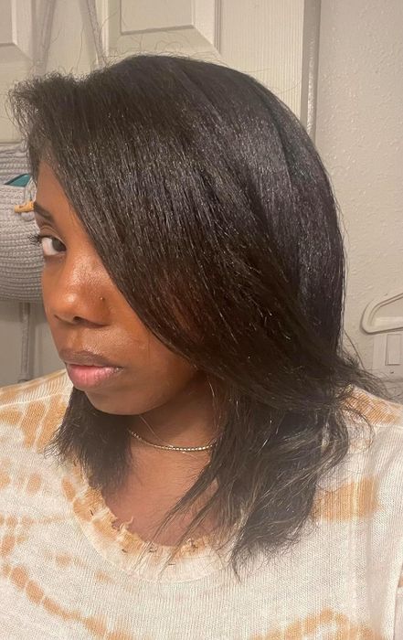 A black reviewer showcasing glossy, straightened hair that falls just past the shoulders.