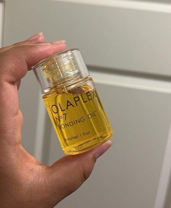 A hand holds a bottle of Olaplex No.7 Bonding Oil