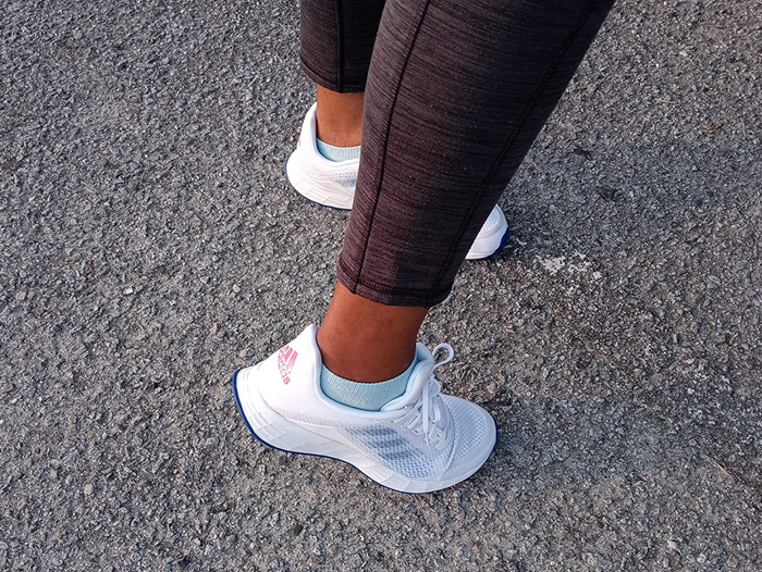 A reviewer showing a back view of Adidas sneakers