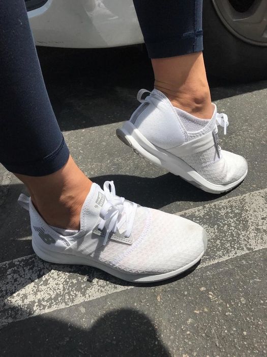 A reviewer wearing white sneakers with a breathable mesh exterior.