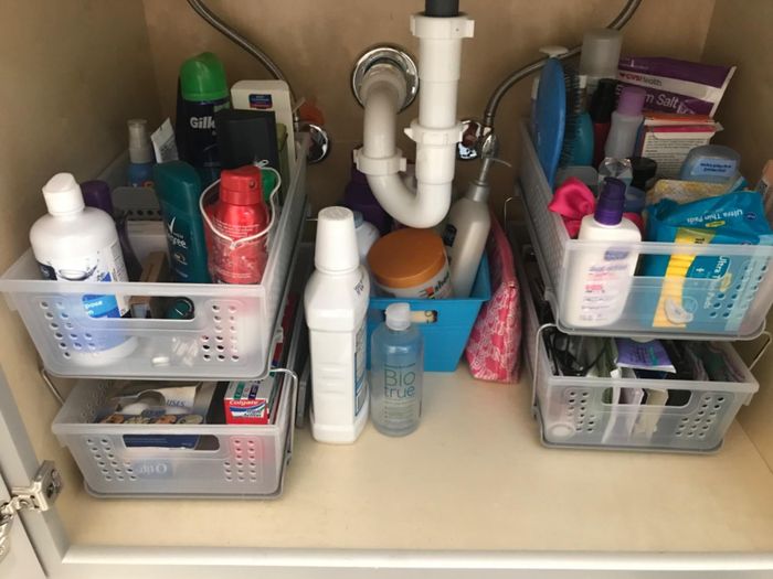 The same under-sink cabinet, now neatly organized with toiletries in a two-tier organizer