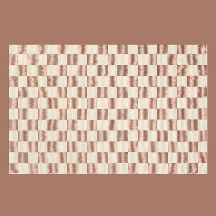 A rug featuring a rust and cream checkered design on a beige backdrop