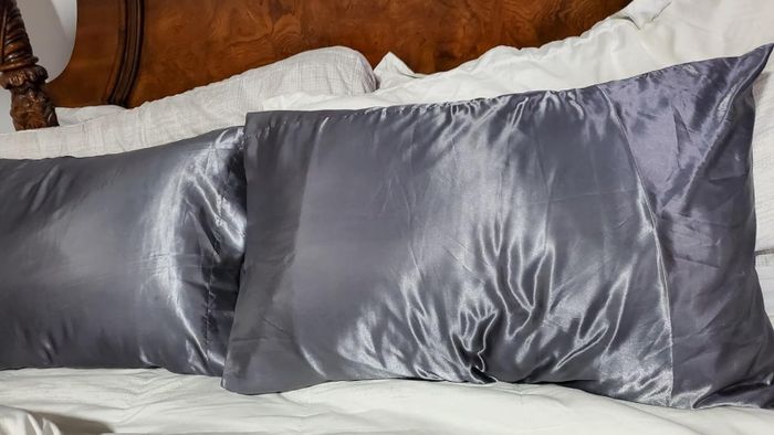 Two sleek satin pillowcases placed on a neatly arranged bed with white linens.