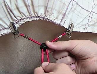 A person adjusting the bedsheet suspenders to ensure a snug fit