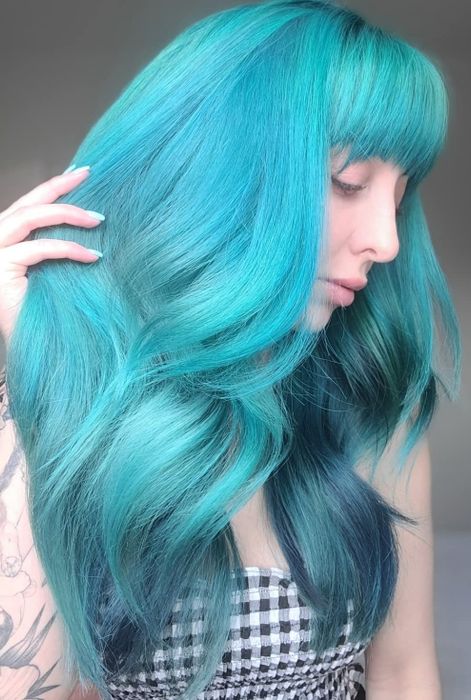 The same person rocking vibrant teal hair in a wavy style