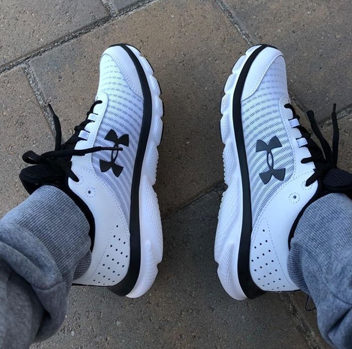 A reviewer wearing black and white sneakers with air holes around the heel and breathable mesh on the sides and toe box