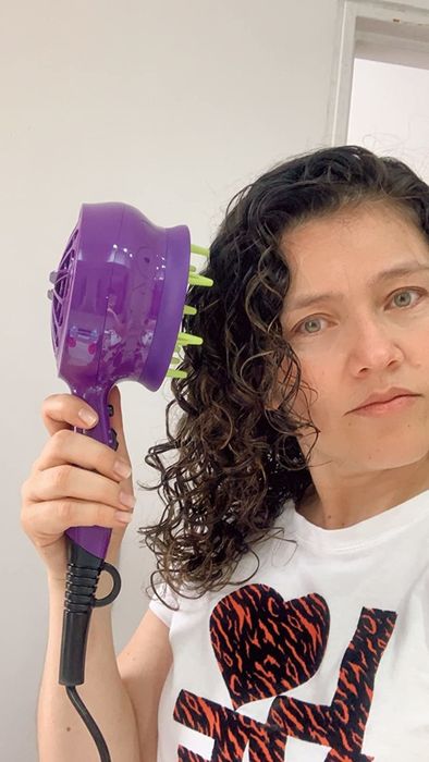 A reviewer using the diffuser attachment on their curly hair.