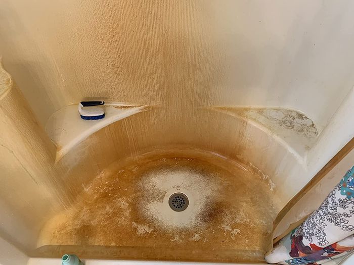 Reviewer’s before image of a shower with orange hard water stains