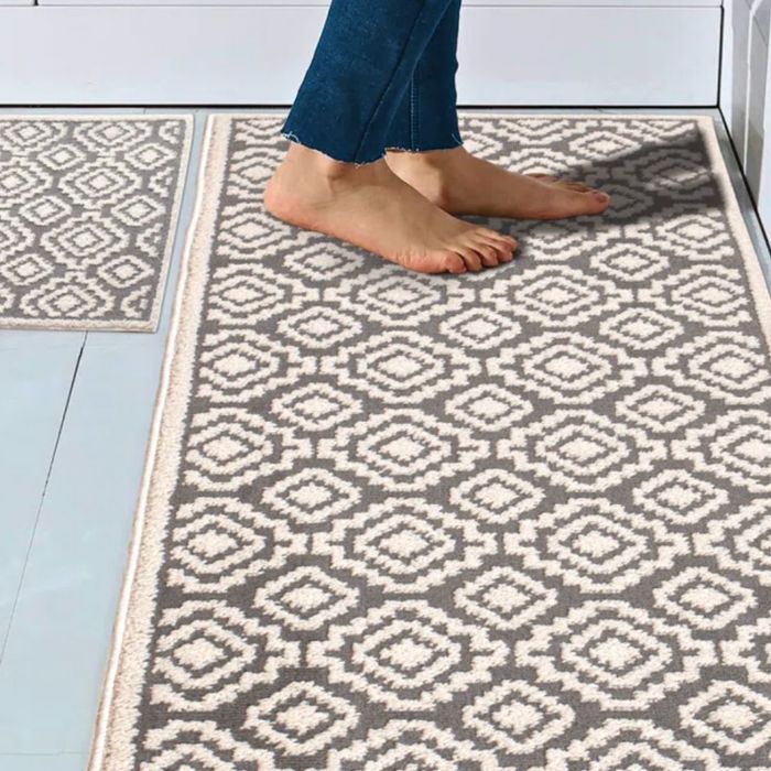 A person standing on a neutral-colored rug with a diamond pattern in a kitchen