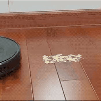 A reviewer’s gif showing the vacuum picking up a pile of food crumbs on the floor