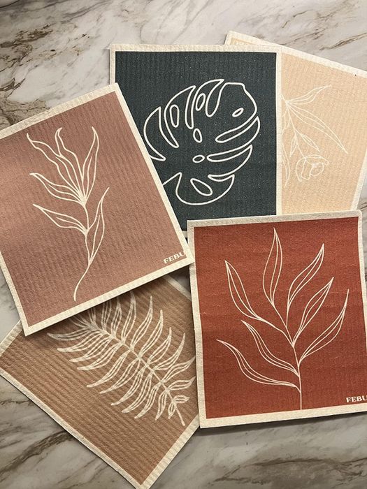 A variety of Swedish dishcloths featuring leaf patterns, arranged on a marble surface.