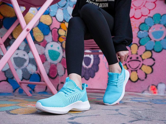 A model sitting down while wearing blue SDolphin sneakers