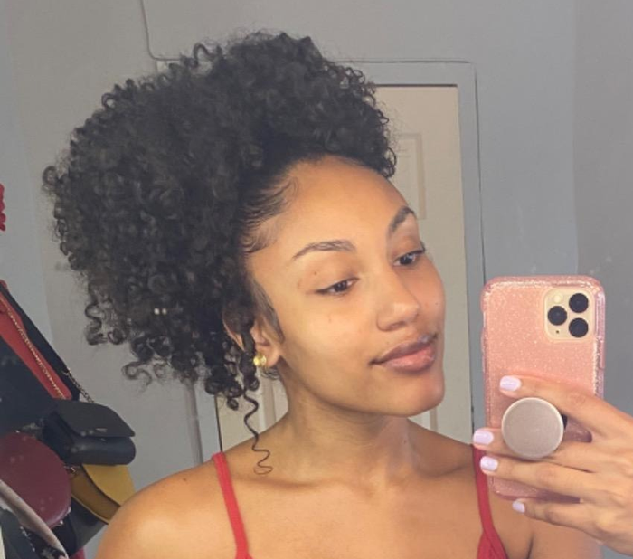 A reviewer with curly hair styled into a high puff ponytail using the hair tie.