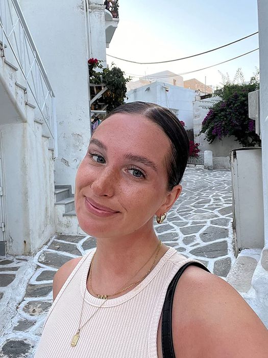 A reviewer showcasing a polished slicked-back bun achieved using the hair wax stick.