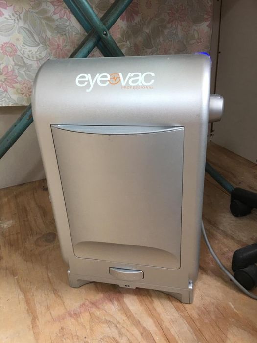 A silver EyeVac stationary vacuum cleaner, neatly placed against a wall, ready for use.