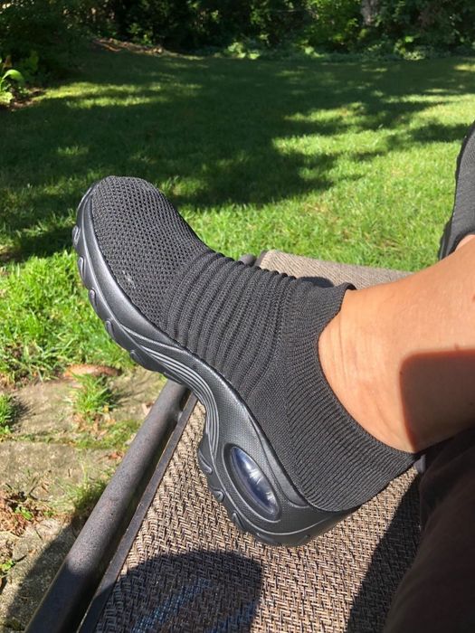 A reviewer wearing sock-sneakers in pure black