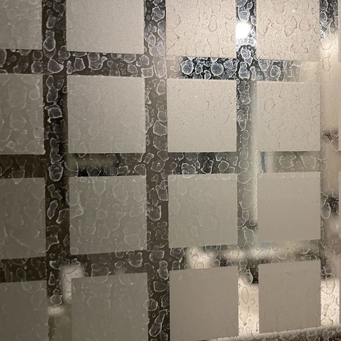 A reviewer photo of a glass shower door covered in hard water stains