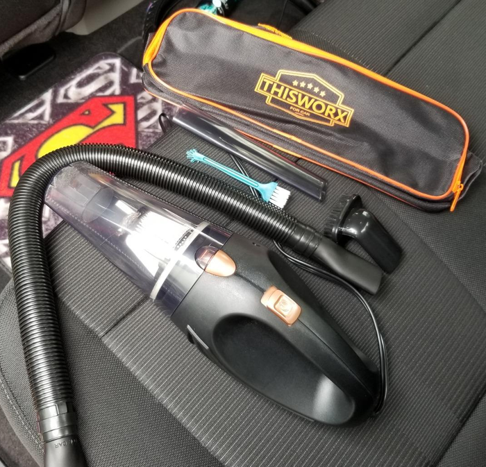 A reviewer photo of the portable vacuum, travel case, and included detail attachments