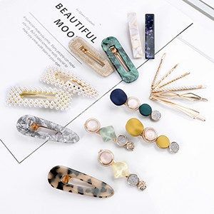 A set of clips and pins, including gold, pearl, tortoiseshell acrylic, and embellished designs