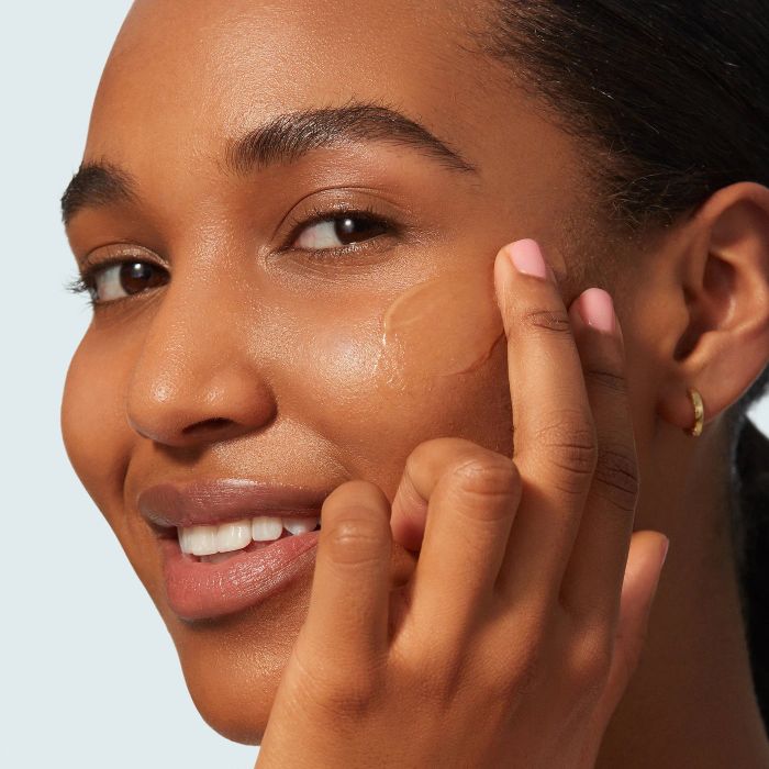 model applying sunscreen to their face