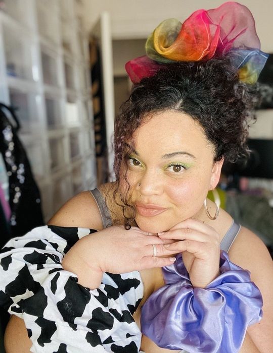 Kayla rocking a giant rainbow tulle scrunchie in her hair, with the cow and lavender versions styled around her wrists