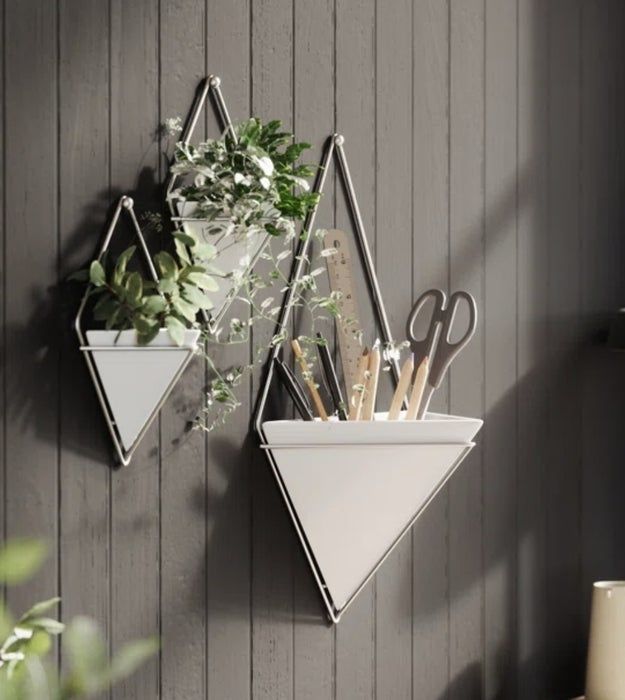Triangular planters mounted on a wall, filled with plants and office supplies