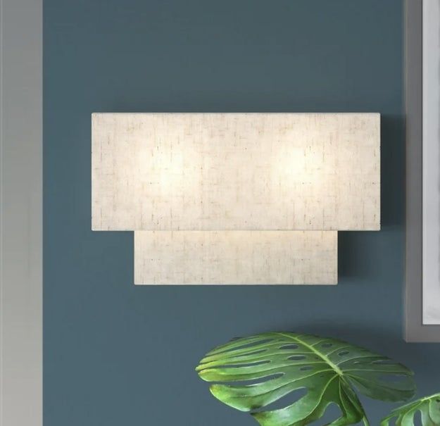 A wall-mounted light fixture positioned above a large indoor plant