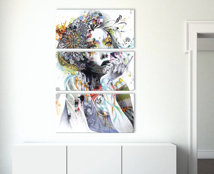 A three-panel abstract art canvas featuring a blend of floral and whimsical designs, placed on a white cupboard