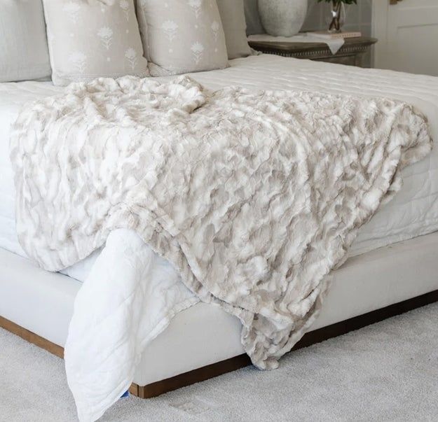 A plush blanket elegantly draped over the corner of a bed