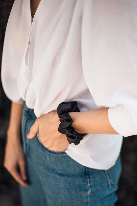 A model wearing a black scrunchie around their wrist
