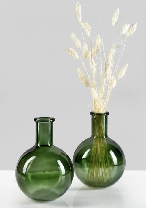 Two vases filled with dried white wheat stalks, placed on a pristine white surface