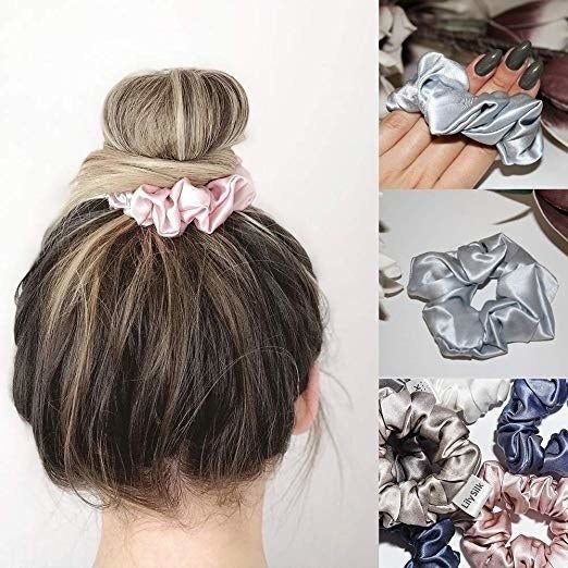 A model sporting a pink scrunchie, with the gray and blue versions displayed beside it