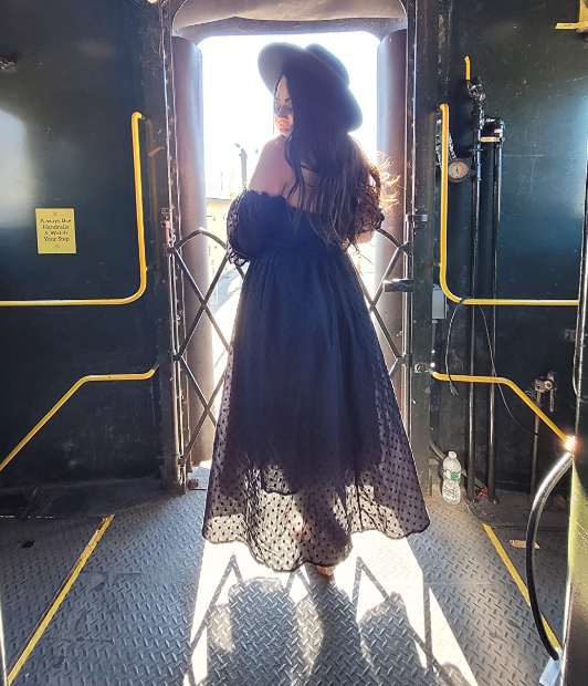 reviewer wearing a black dress with sheer panels that catch the sunlight beautifully