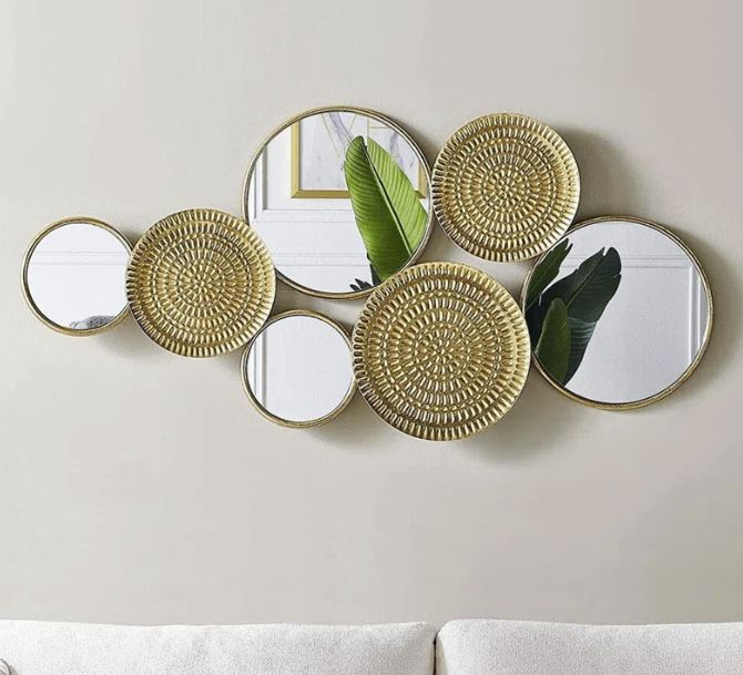 A decorative wall piece combining mirrors and woven circular patterns, hung above a light-colored sofa