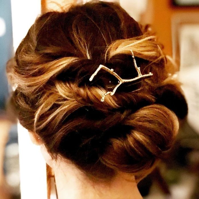 A reviewer showcasing a gold branch-shaped pin in an elegant updo