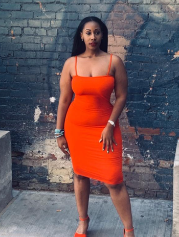 reviewer posing in a spaghetti strap dress in front of a vibrant wall mural