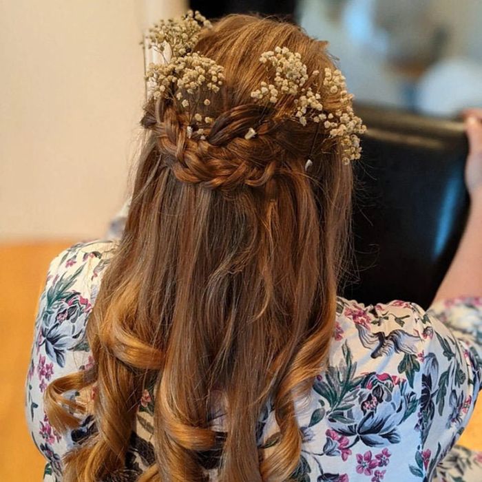 A person styling their hair with several baby’s breath pins for a beautiful, floral touch.