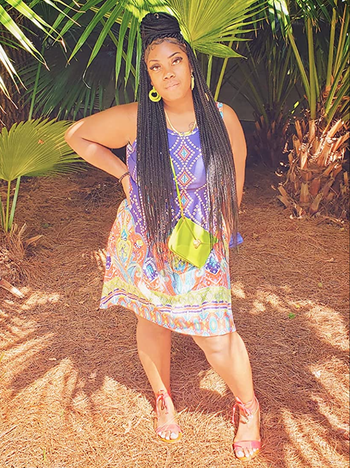 reviewer wearing a blue sleeveless t-shirt dress with vibrant yellow, orange, and light blue patterns