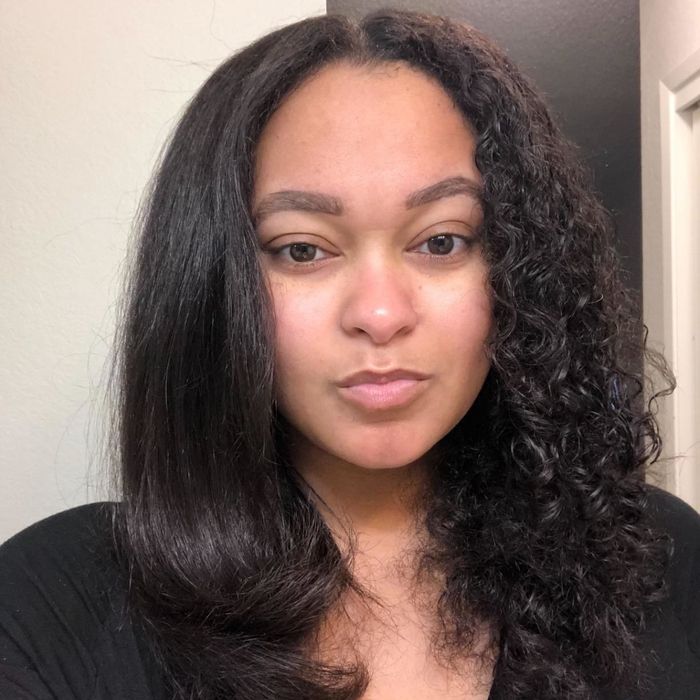 A reviewer demonstrating how they’ve straightened half of their tightly curled hair using the hot air brush