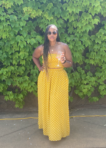 reviewer wearing the yellow dress set in front of a lush, tall bush