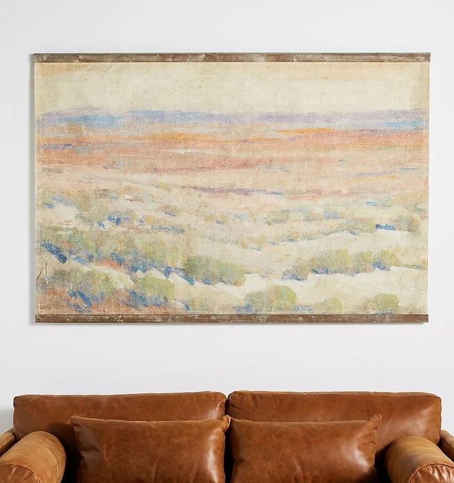 A large abstract painting displayed above a brown leather sofa