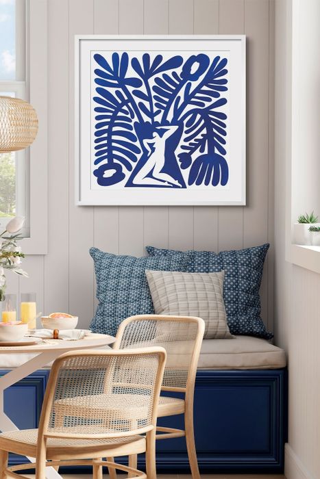 A botanical silhouette artwork hangs above a cushioned bench in a cozy breakfast nook