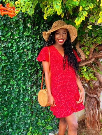 reviewer wearing the red dress accessorized with a hat and matching purse