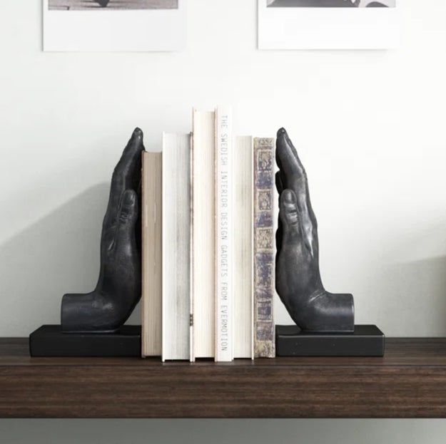 A bookshelf featuring books neatly organized with a pair of hand-shaped bookends