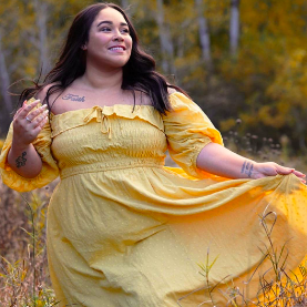 reviewer modeling the dress with sleeves down, highlighting their shoulders. The dress is snug at the top and flares out gracefully at the bottom.
