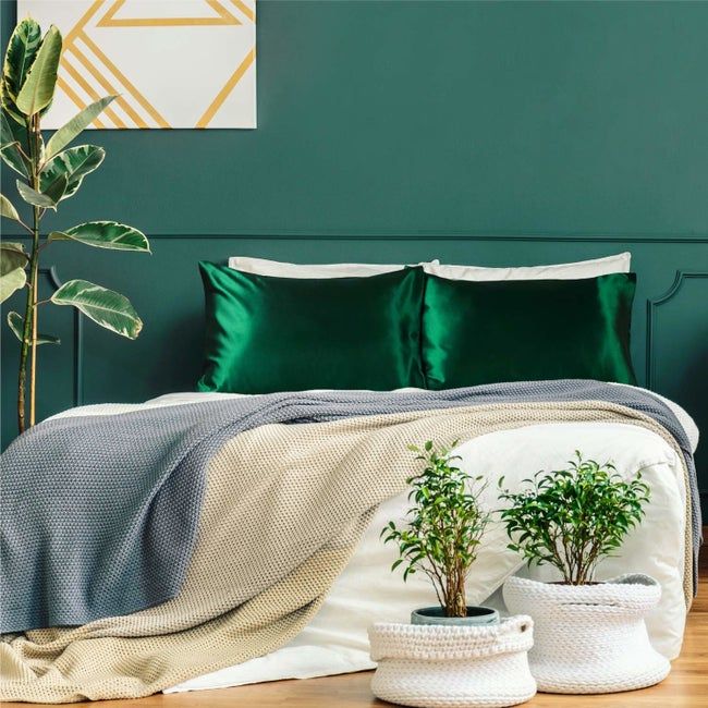 A stock image of a bed adorned with luxurious green satin pillows