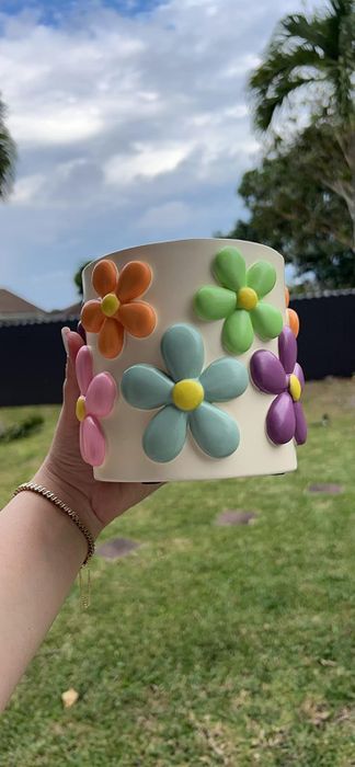 A reviewer holding a planter adorned with a floral design.