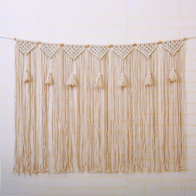 A macramé wall hanging made of natural rope with decorative tassels