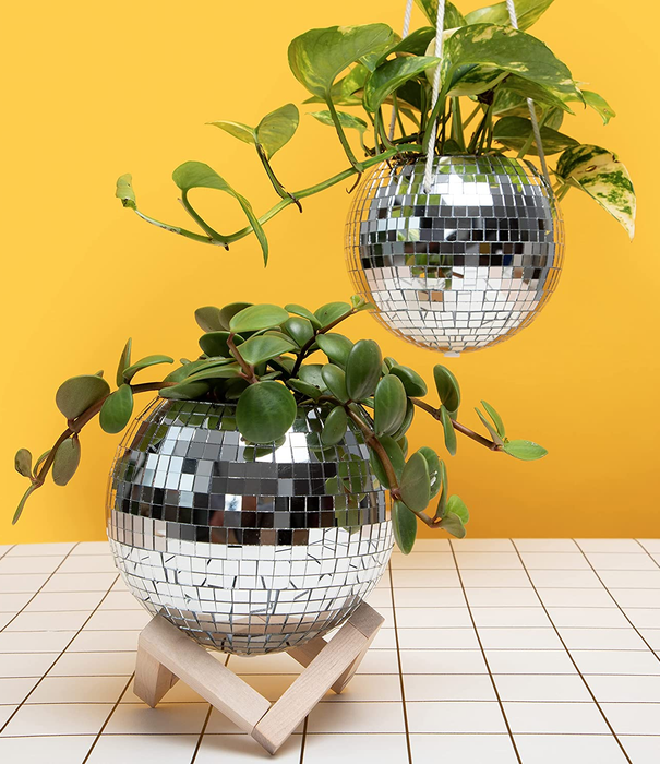 Two disco ball planters with plants: one hanging from rope and the other resting on a stand, both adding a quirky touch to any space.